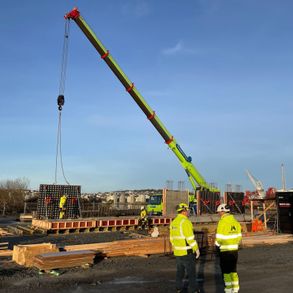 Betongelement løftes på plass av stor kranbil