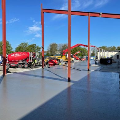Betongarbeid utendørs med arbeidsbiler i bakgrunnen