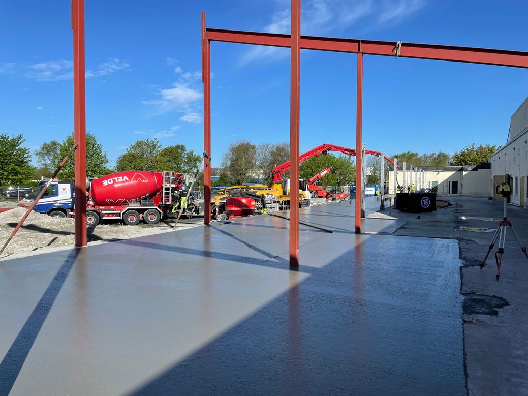 Betongarbeid utendørs med arbeidsbiler i bakgrunnen